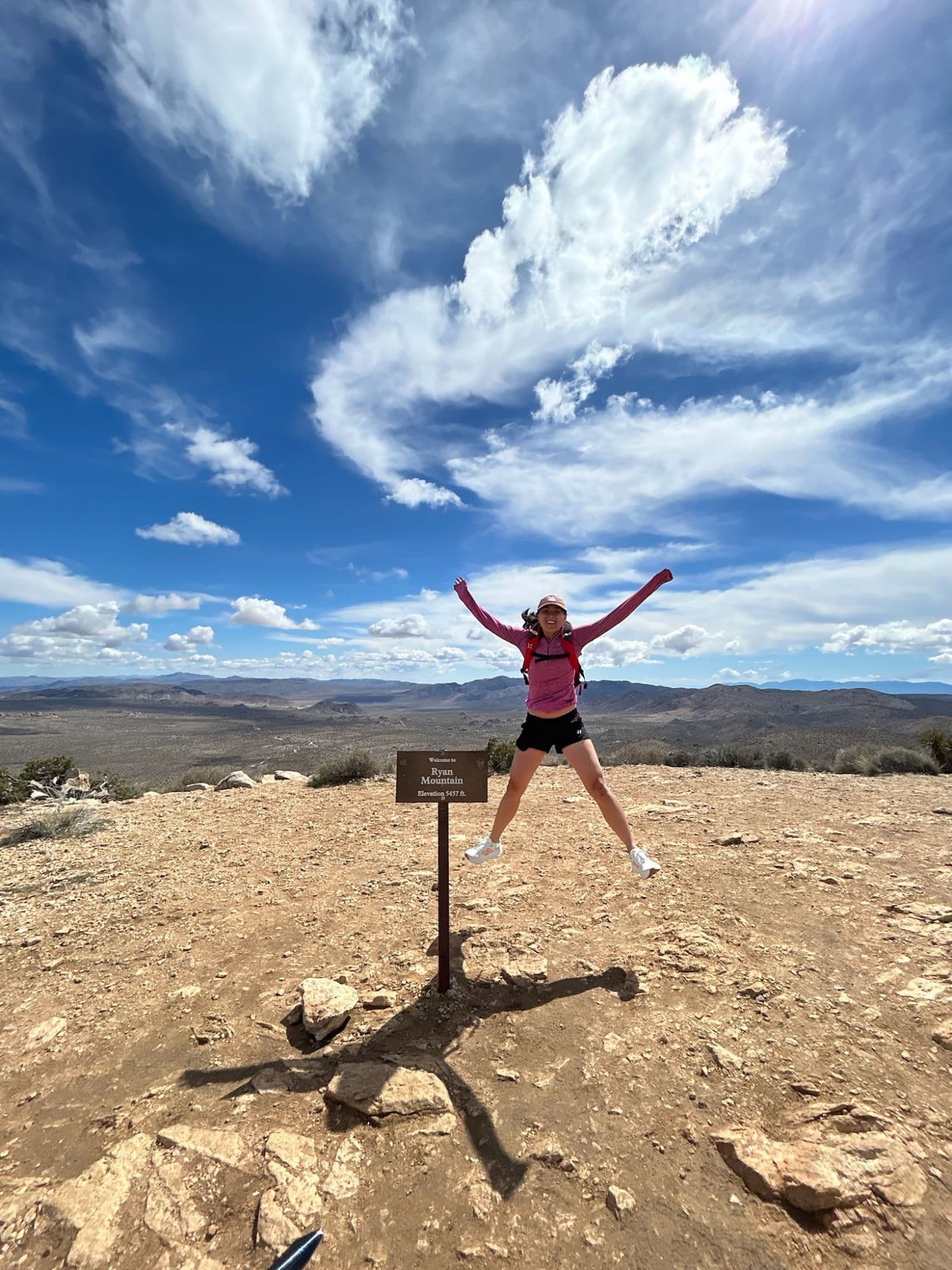 Roslyn jumping at the Ryan Mountain summit sign in Joshua Tree National Park